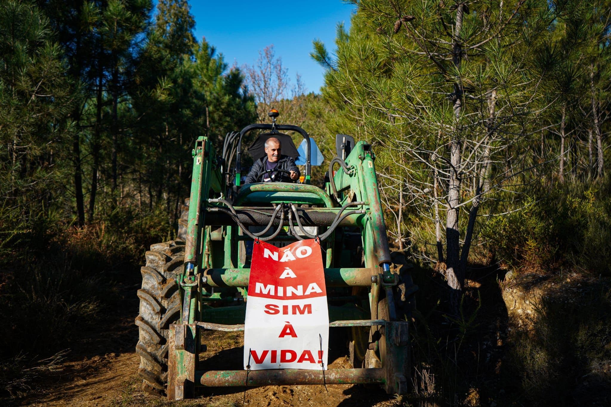 Pessoa em trator com cartaz contra a mina